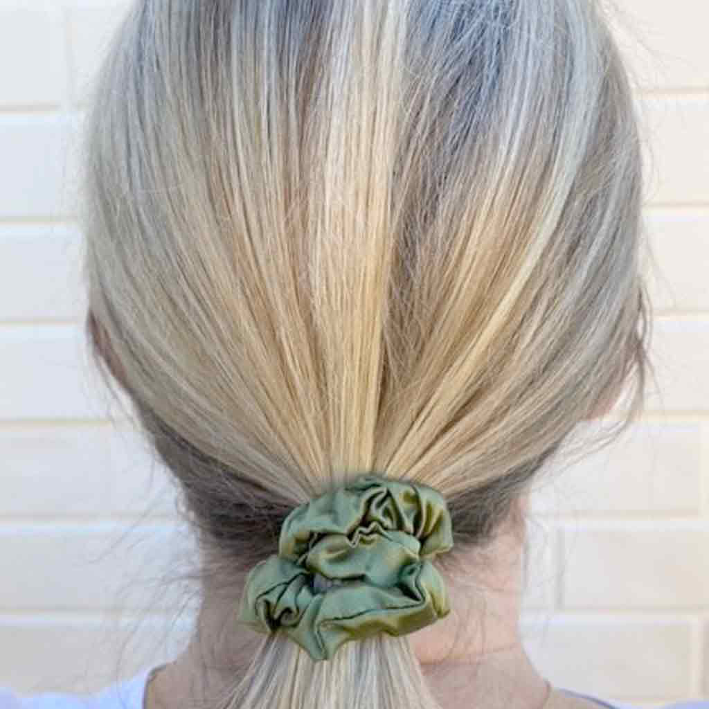 Woman wearing an avocado green silk scrunchie in her hair