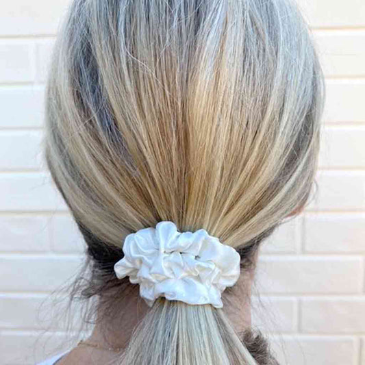 Woman wearing an ivory white silk scrunchie in her hair