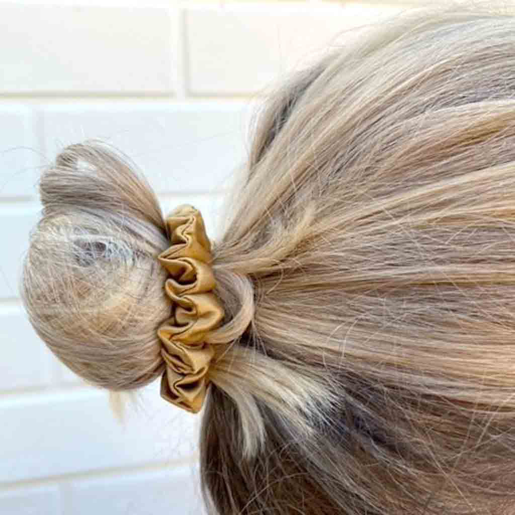 Woman wearing a gold silk scrunchie in her hair