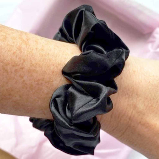 Medium black silk scrunchie on a woman's wrist