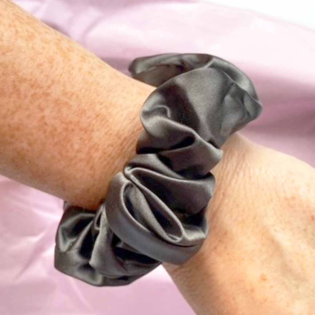 Medium charcoal grey silk scrunchie on a woman's wrist