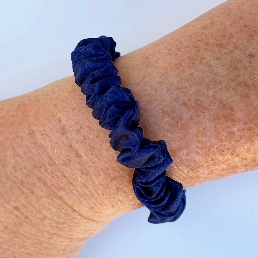 Slender navy blue silk scrunchie made from 100% Mulberry silk, shown on white background