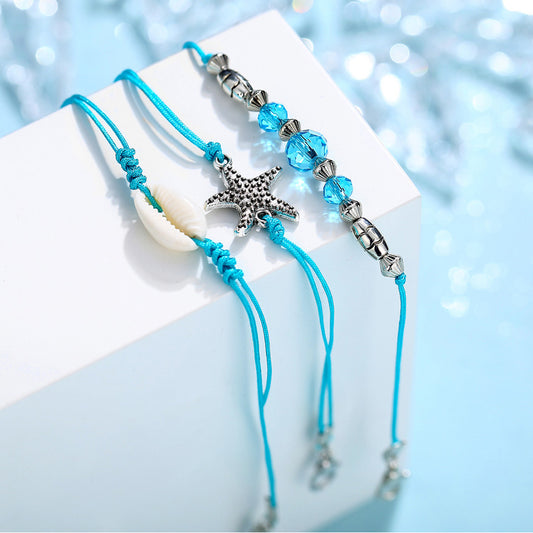 Three-piece bohemian beach anklet set featuring teal wax rope, a natural seashell, a starfish charm, and blue beads.