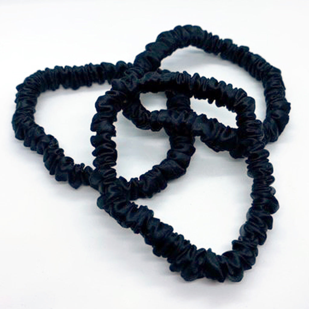 Set of three black skinny silk scrunchies made from pure Mulberry silk, displayed in mesh gift pouch