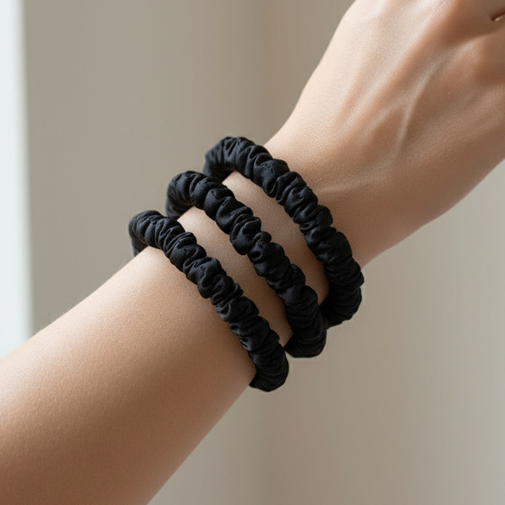 Set of 3 black skinny silk scrunchies made from pure mulberry silk on a woman's wrist