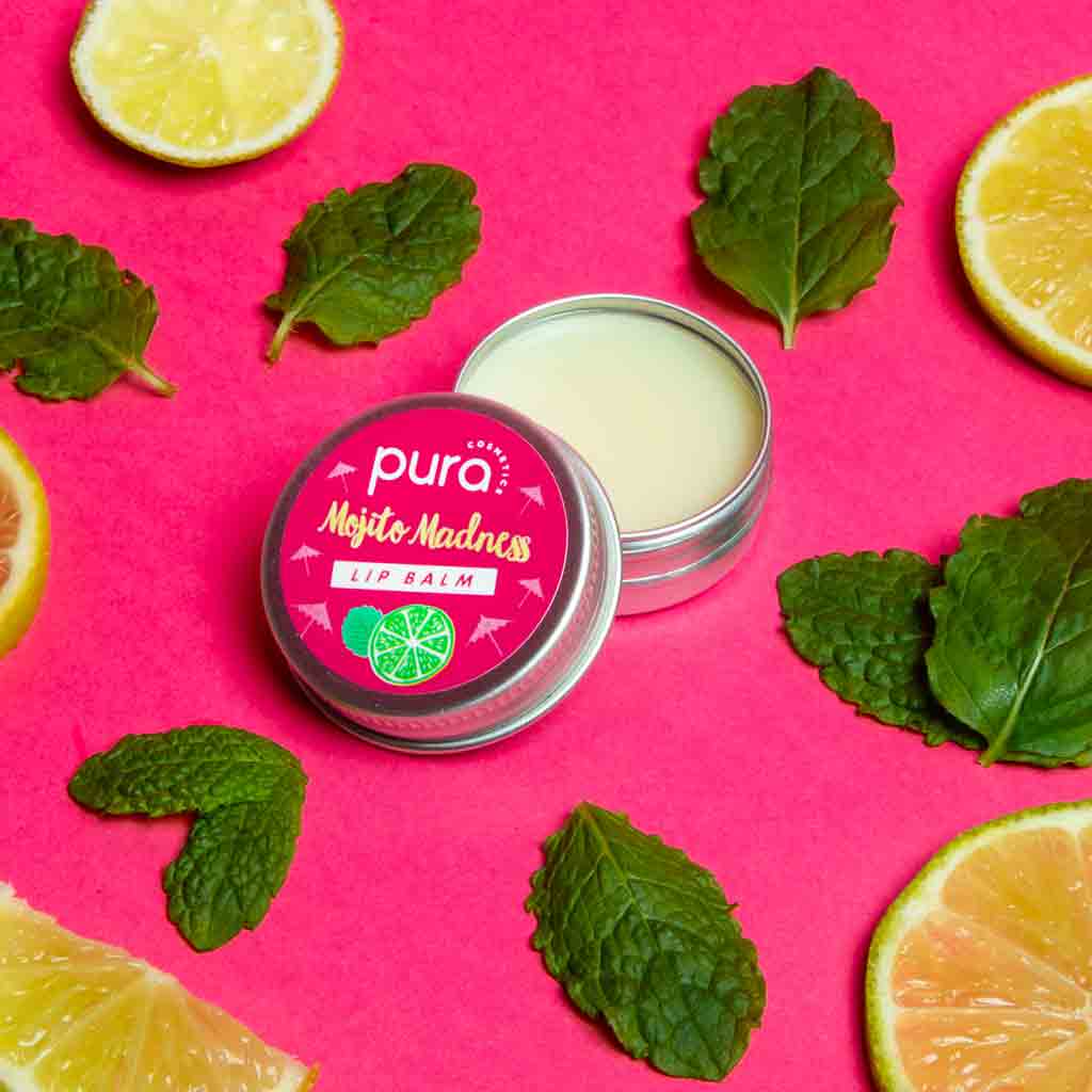 A jar of pura cosmetics mojito madness lip balm surrounded by mint and lemons