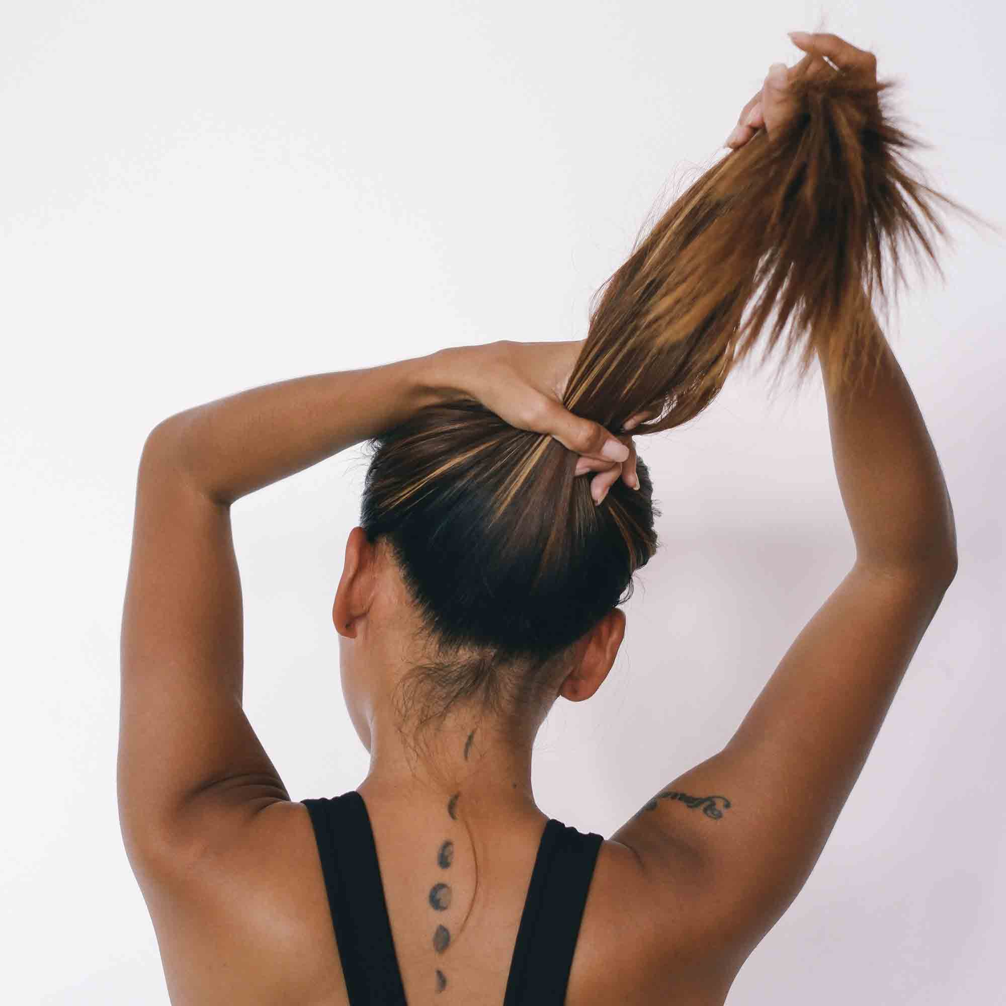 Woman with a tattoo about to put her hair in a silk scrunchie