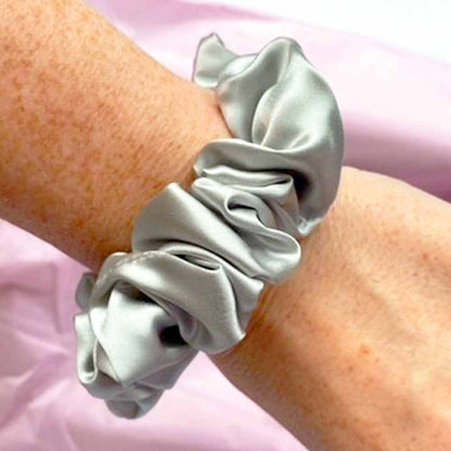 Medium silver silk scrunchie on a woman's wrist