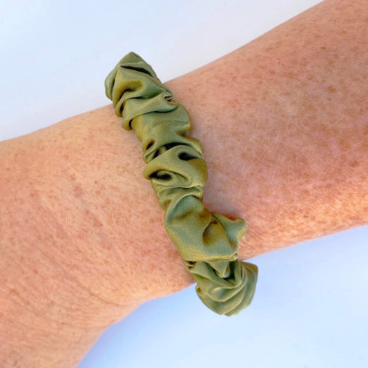 Avocado green silk scrunchie on a woman's wrist