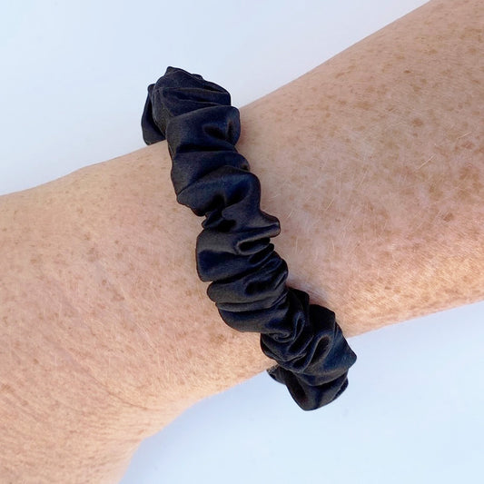 Small black silk scrunchie on a woman's wrist