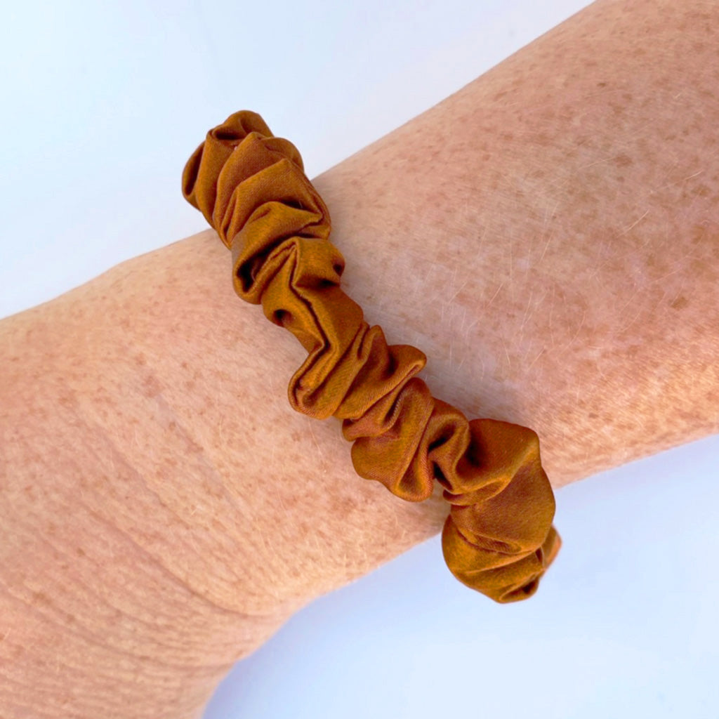 Copper brown silk scrunchies on a woman's wrist