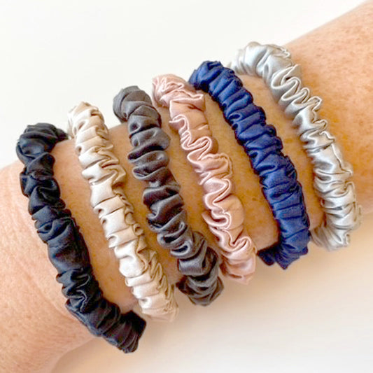 Mulberry silk skinny scrunchies in various colours on a woman's wrist