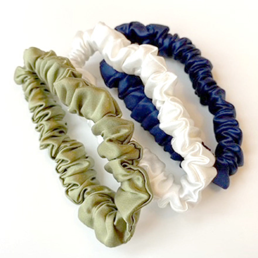 Set of three premium mulberry silk slim scrunchies in green, white, and blue on a white background