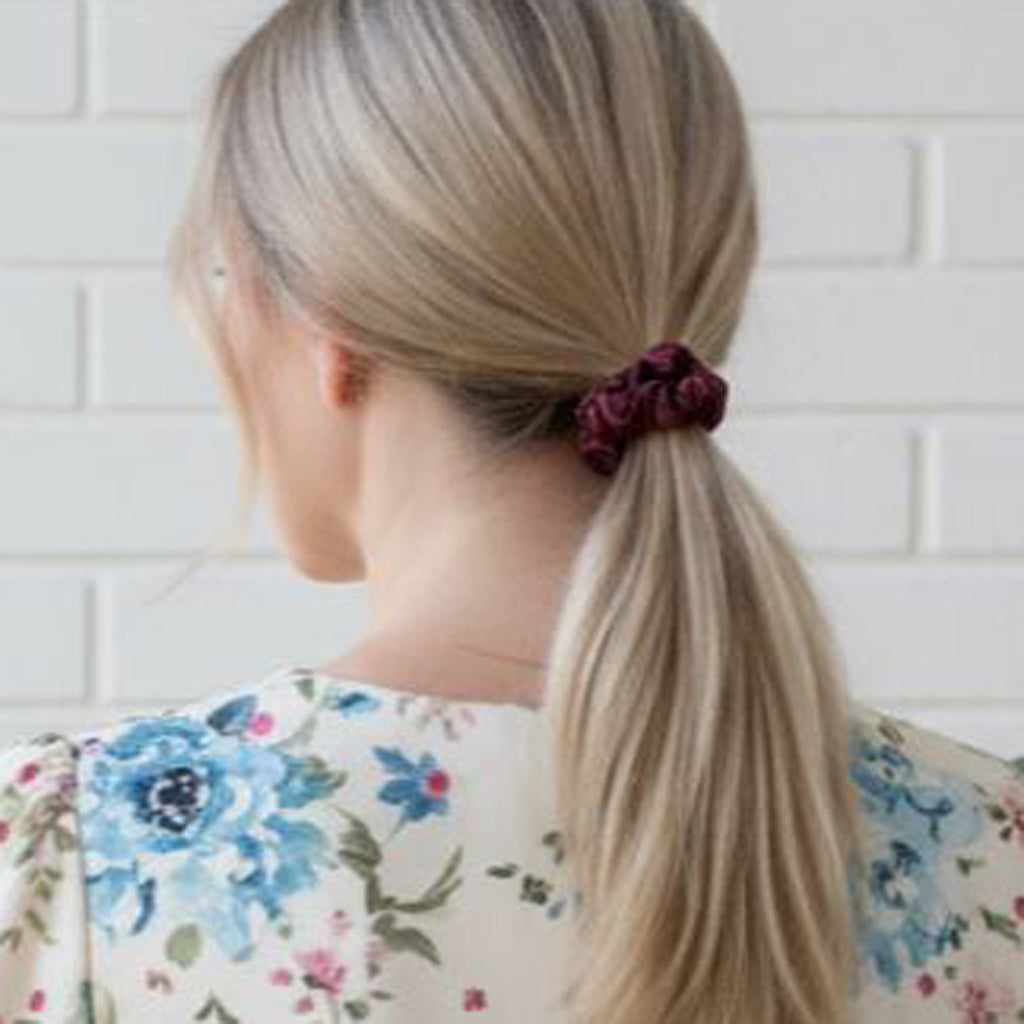 Person with a ponytail wearing a premium mulberry silk plum wine scrunchie