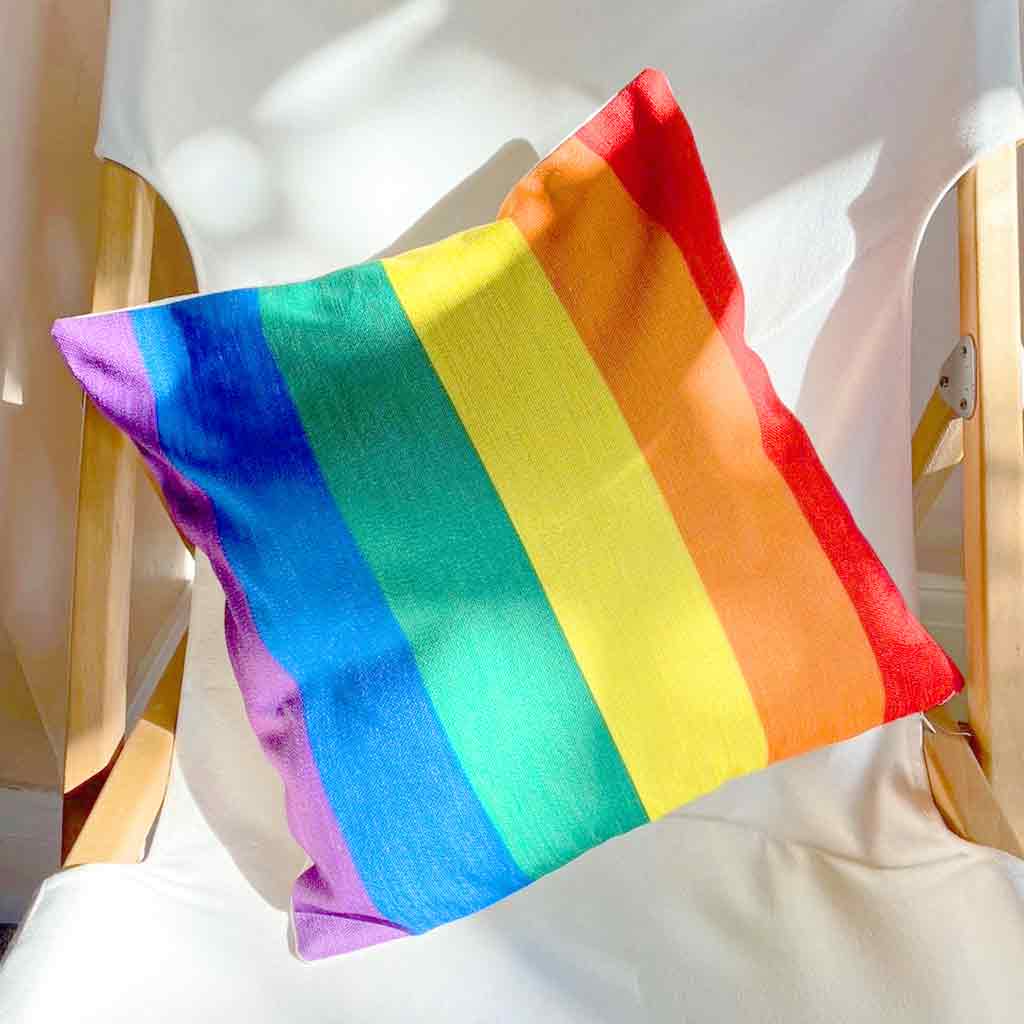 Pride rainbow cushion cover on a chair in the sunlight